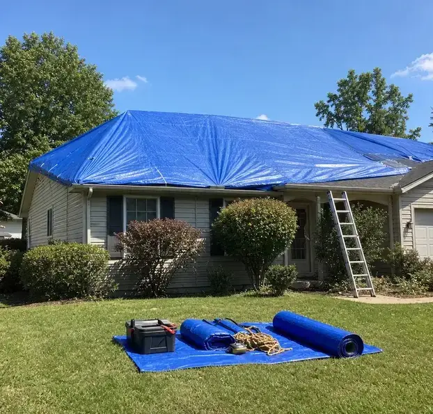Blue roof tarp secured over a house with a ladder and spare tarps on the lawn in Wisconsin Rapids, WI